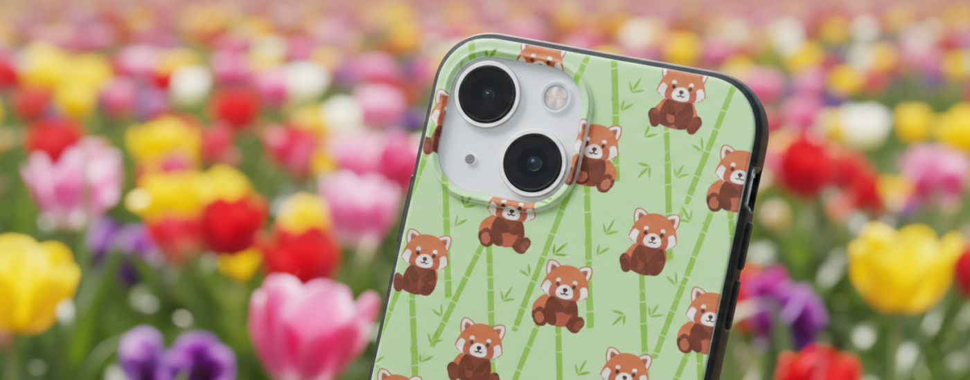 Artimas išmaniojo telefono vaizdas: šviesiai žalias dėklas su mielų animacinių mažųjų pandų ir bambuko stiebų raštu ryškiame, sulietame spalvingų tulpių fone.