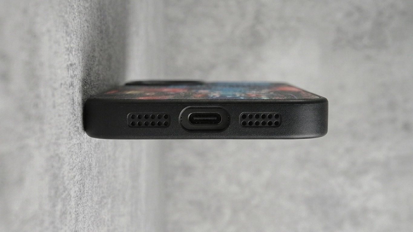 Close-up bottom view of a black KURKIS phone case showing precise cutouts for USB-C charging port and speakers.
